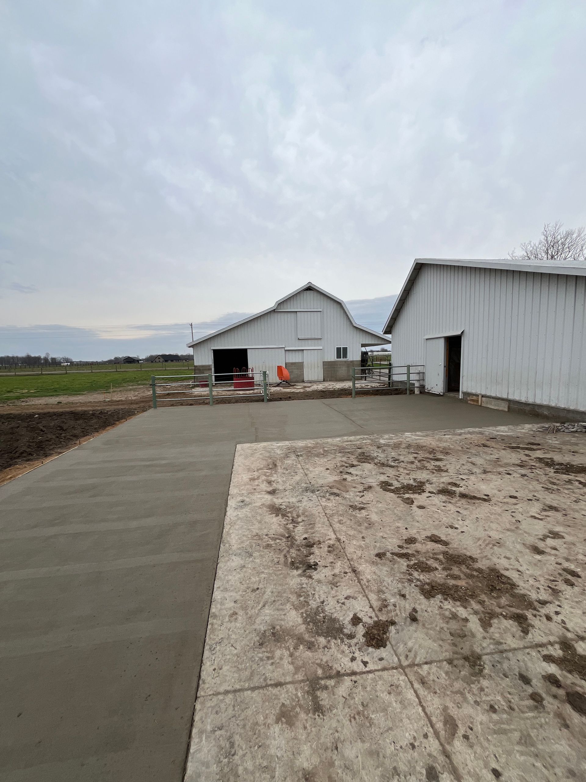 Barns with new concrete driveway on a cloudy day.