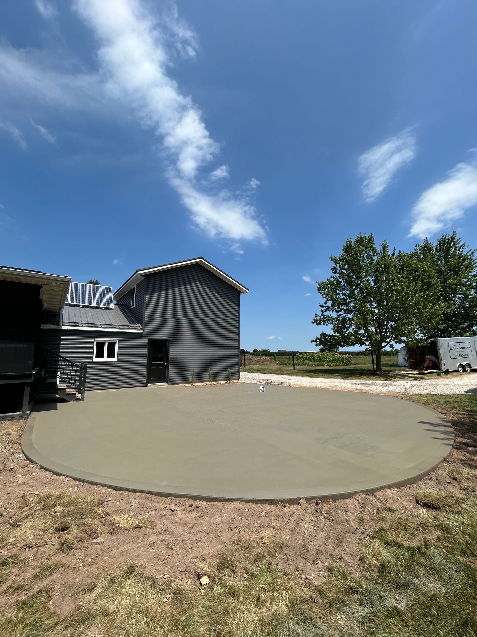 Circular concrete patio outside a building with unique patterned exterior against a blue sky.