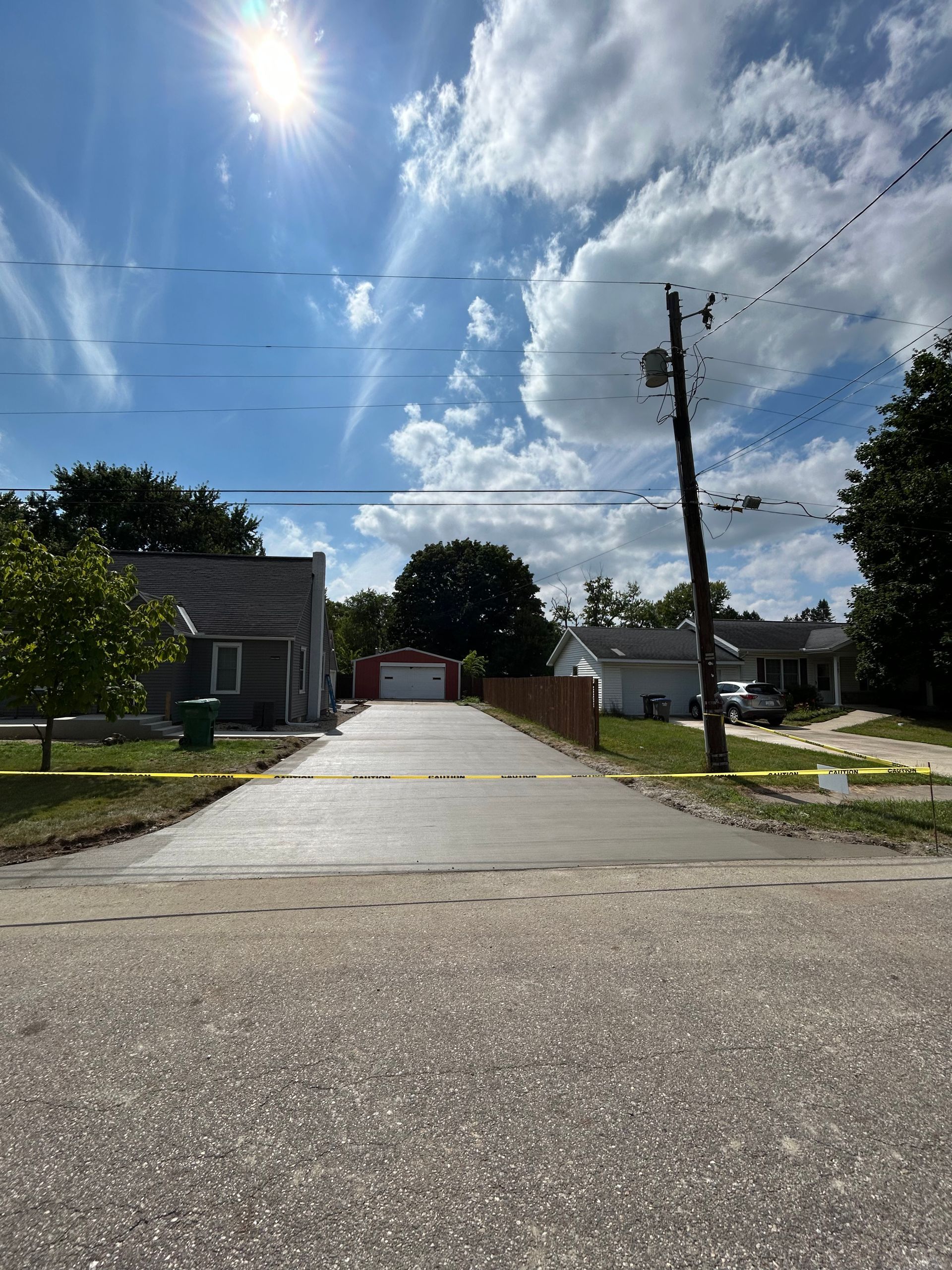 Driveway leading to garage under a bright blue sky with wispy clouds.