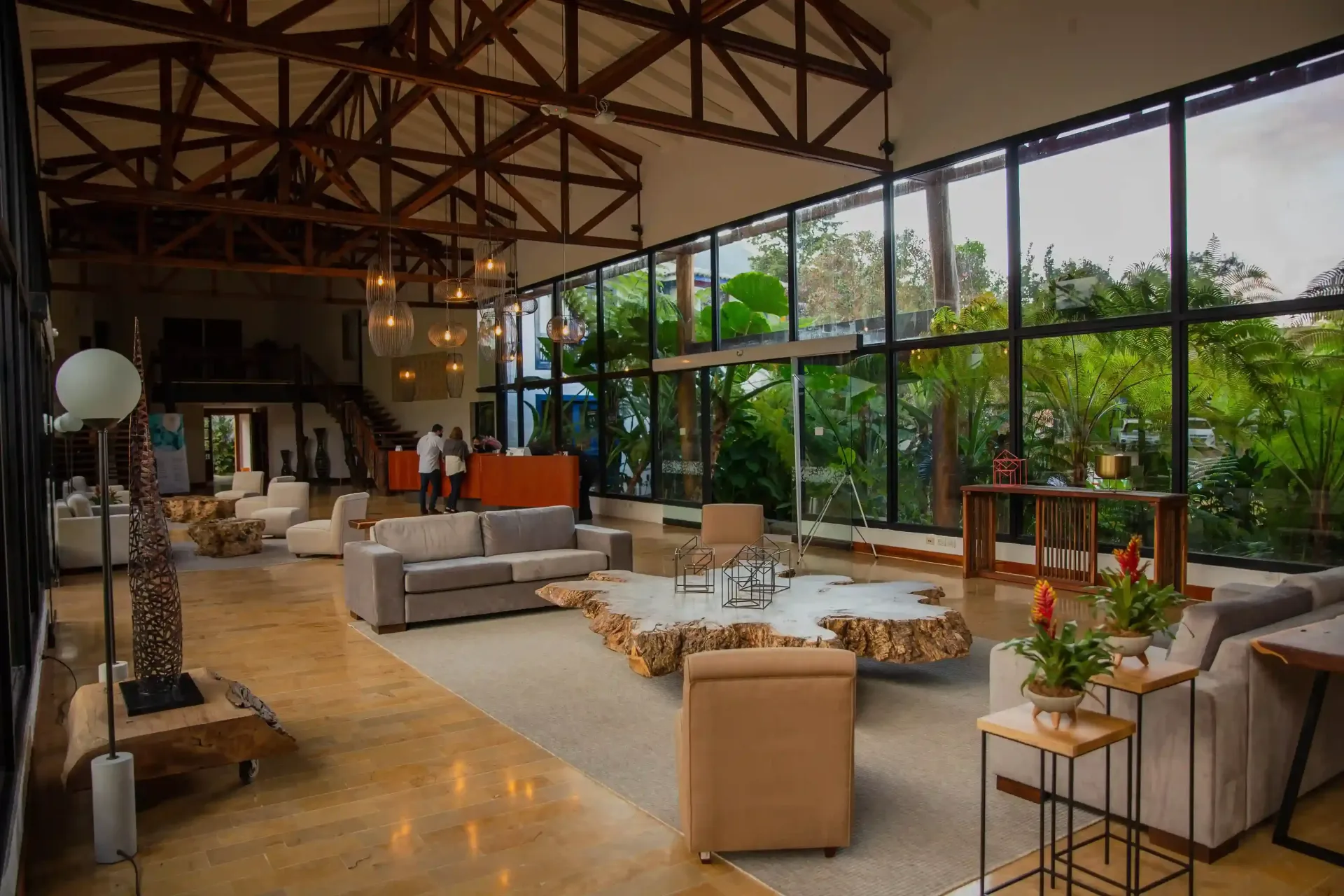 Lobby amplio y moderno del Hotel Termales El Otoño cerca a Manizales, con decoración en madera, ventanales panorámicos, salas de estar elegantes y vista a jardines tropicales.