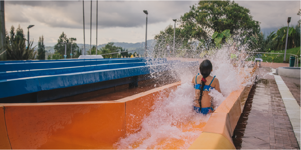 Persona deslizándose por tobogán acuático naranja en Acuaparque Termales El Otoño, plan para qué hacer en Manizales con niños.