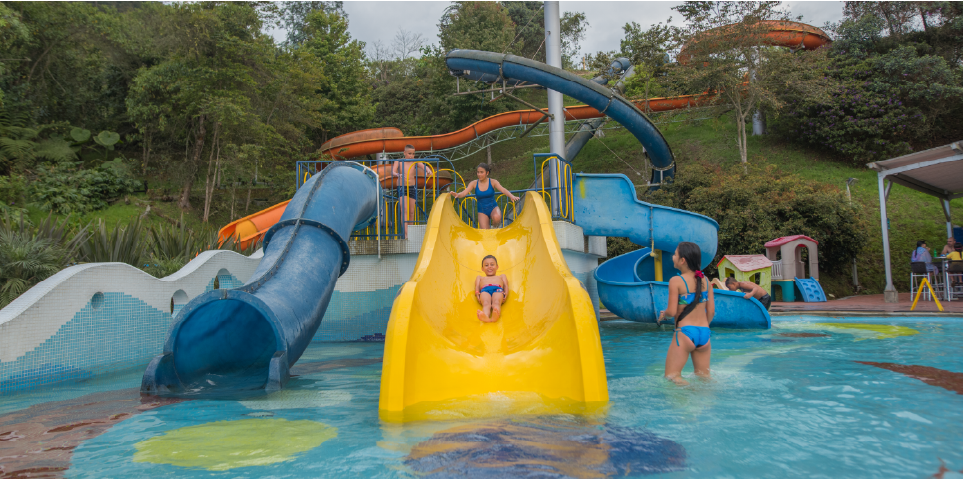 Niños y familias disfrutando toboganes y piscina en Acuaparque Termales El Otoño, termales en Manizales con toboganes.