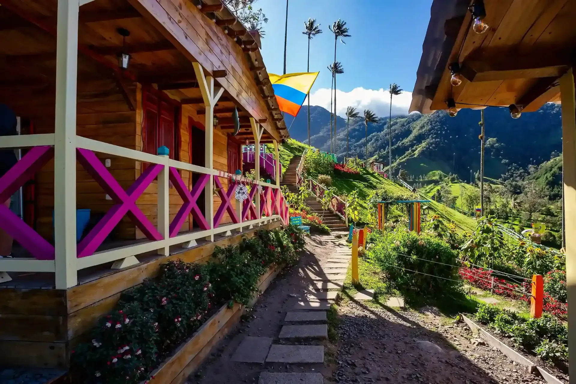 Cabañas de estilo rústico y colorido en zona rural, con paisaje montañoso, palmas de cera y ambiente turístico típico del Eje Cafetero.