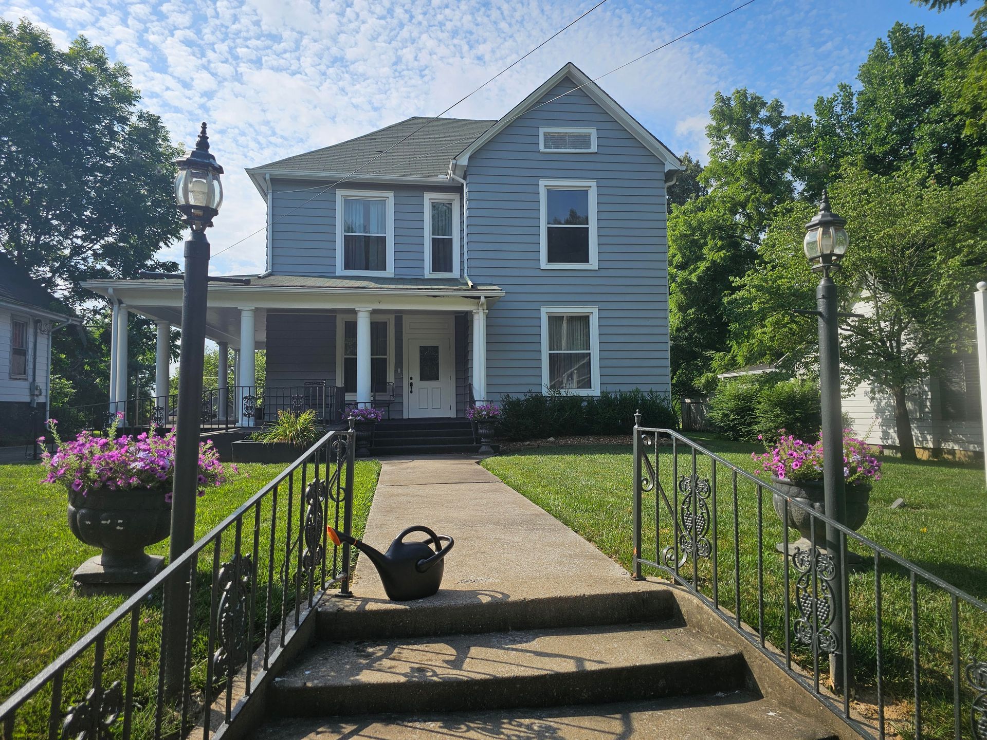 The front door of a house with a porch and plants in front of it.