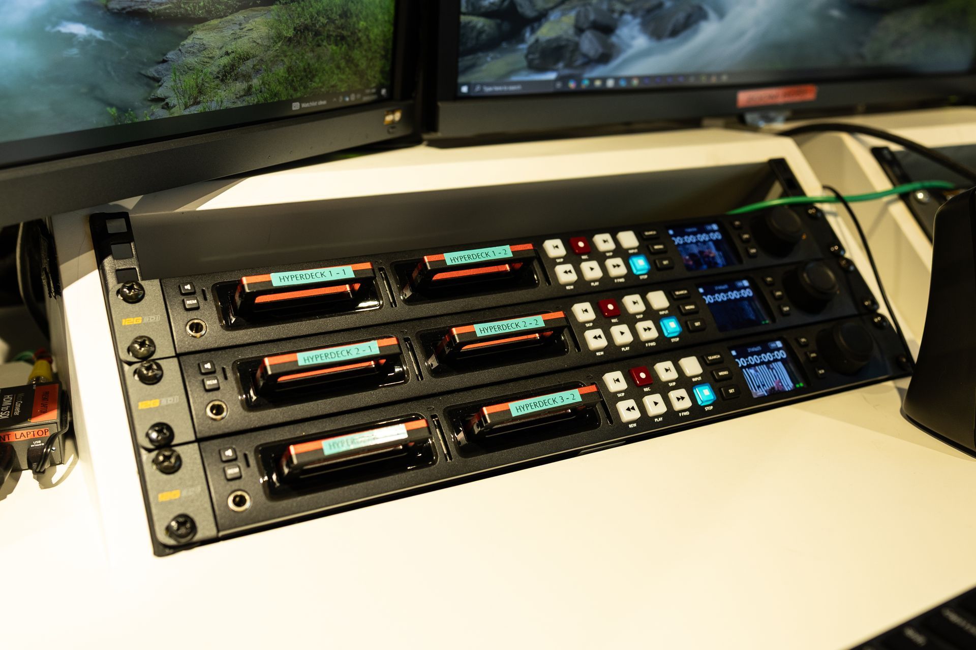 A bunch of batteries are sitting on a table next to a monitor.