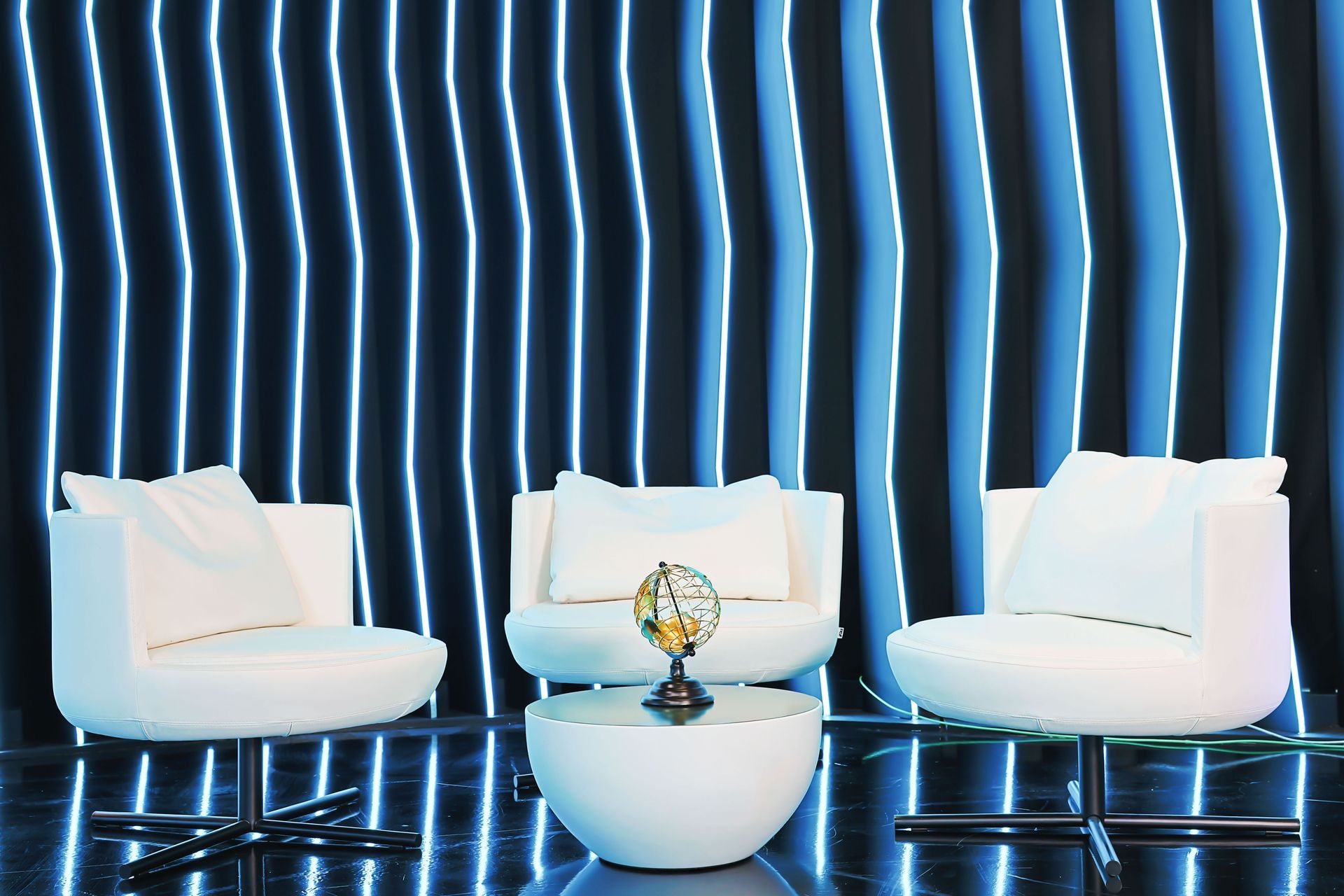 A living room with white chairs and a table with a globe on it