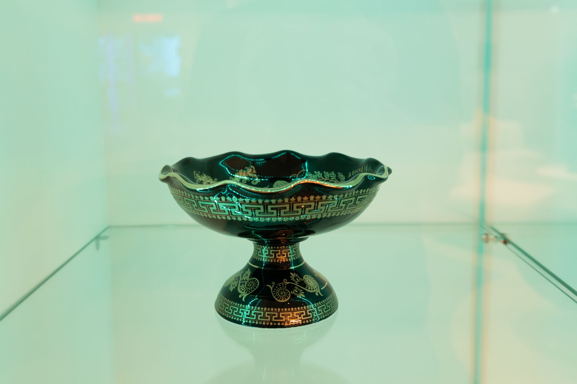 A black bowl is sitting on top of a glass shelf.