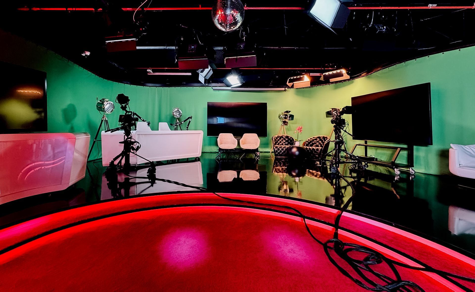 A television studio with a green screen and a red floor.