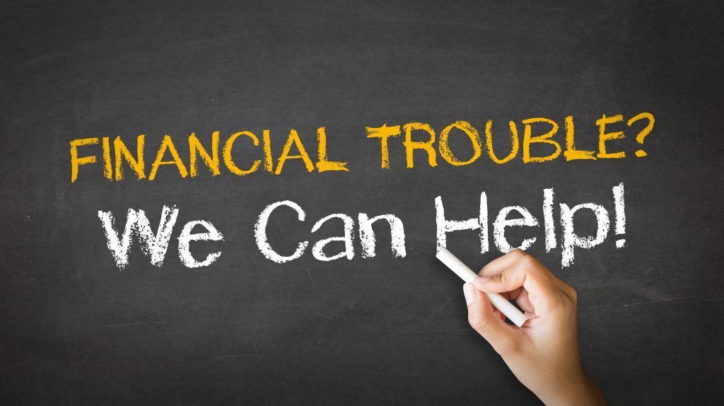 A person is writing on a blackboard that says financial trouble we can help
