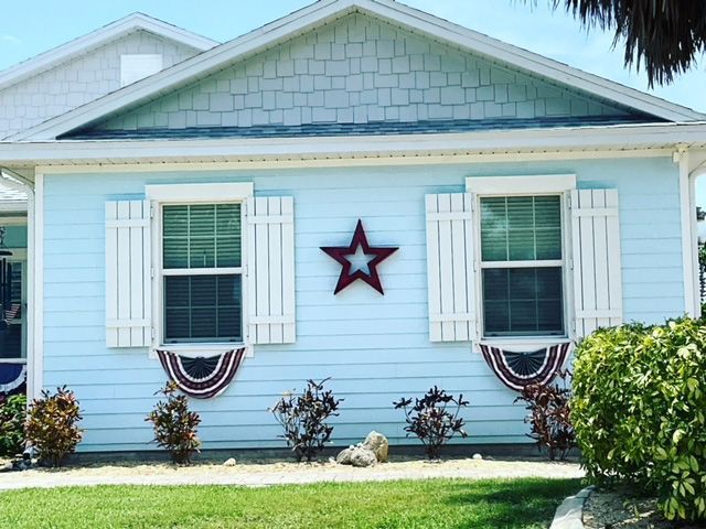 A blue house with white shutters and a red star on the front