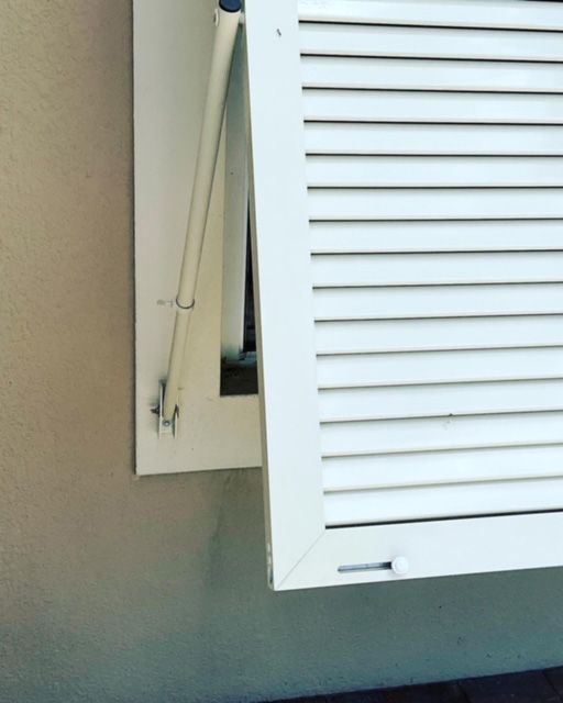 A white window shutter with a pole attached to it