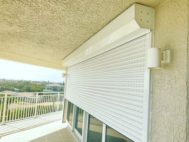 A white roller shutter is on a window on a balcony