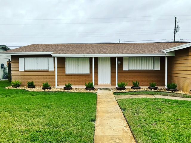 A house with a walkway leading to it and a lush green yard