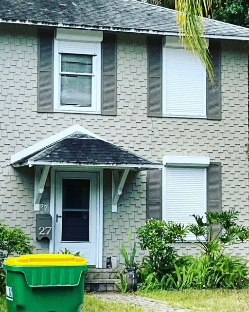 A house with a green trash can in front of it