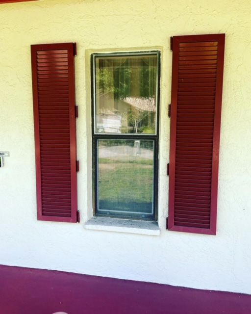 A window with red shutters on a white wall