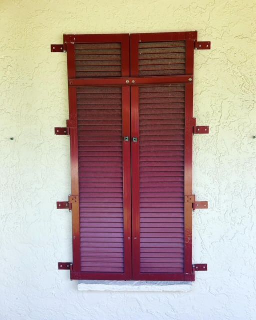 A window with red shutters on a white wall