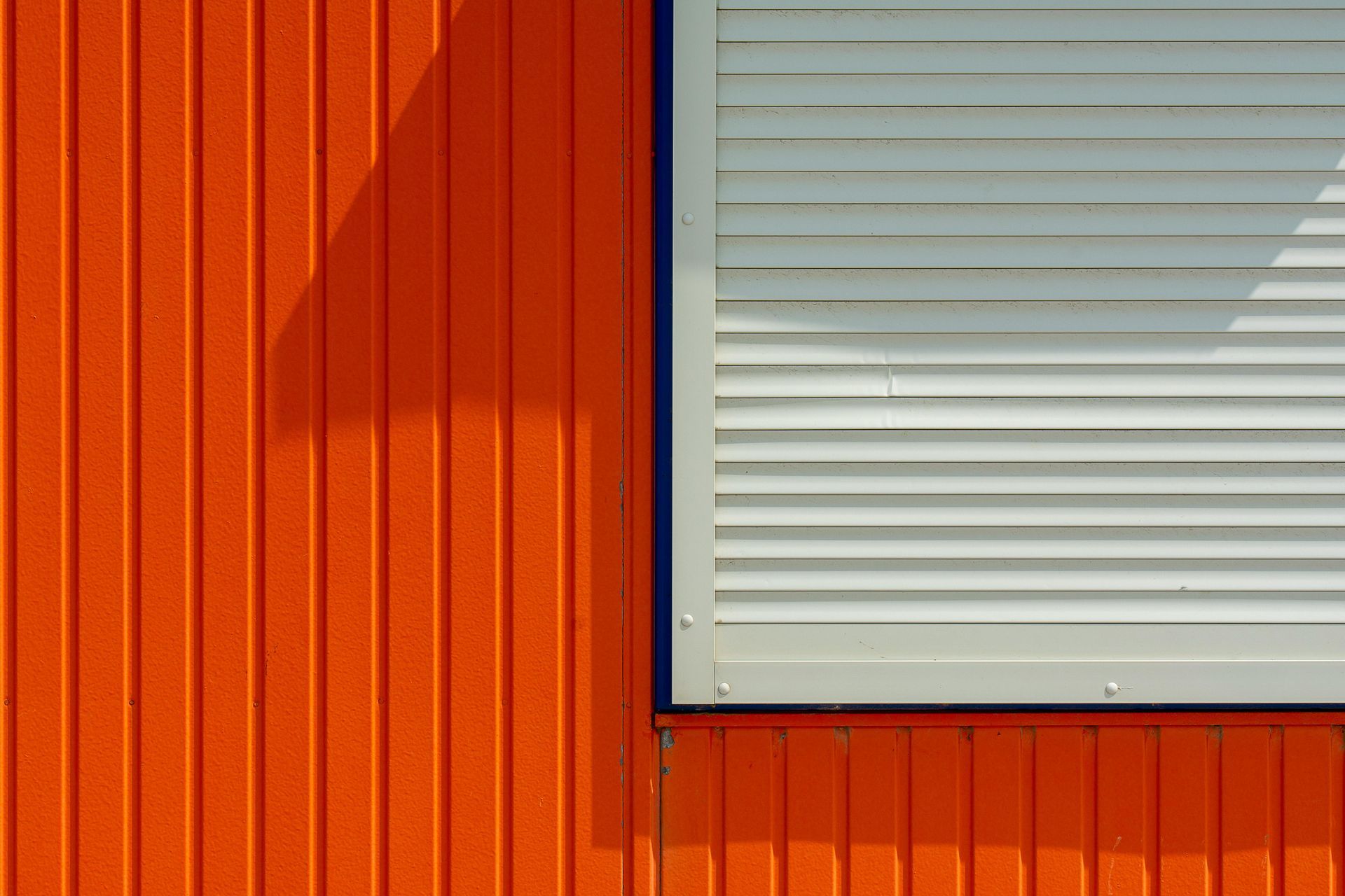 A close up of an orange wall with a white window