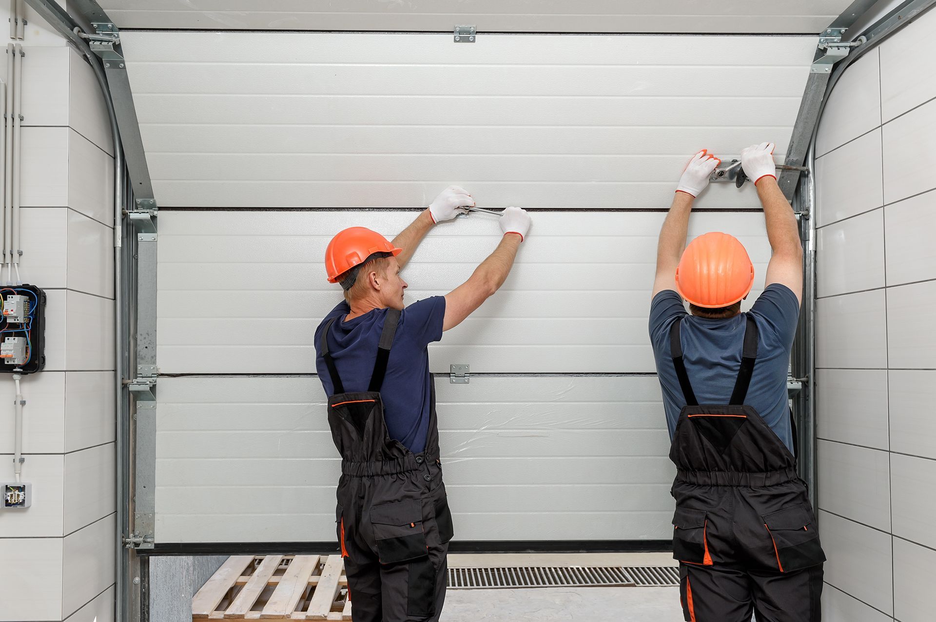 Two men are installing a garage door in a garage