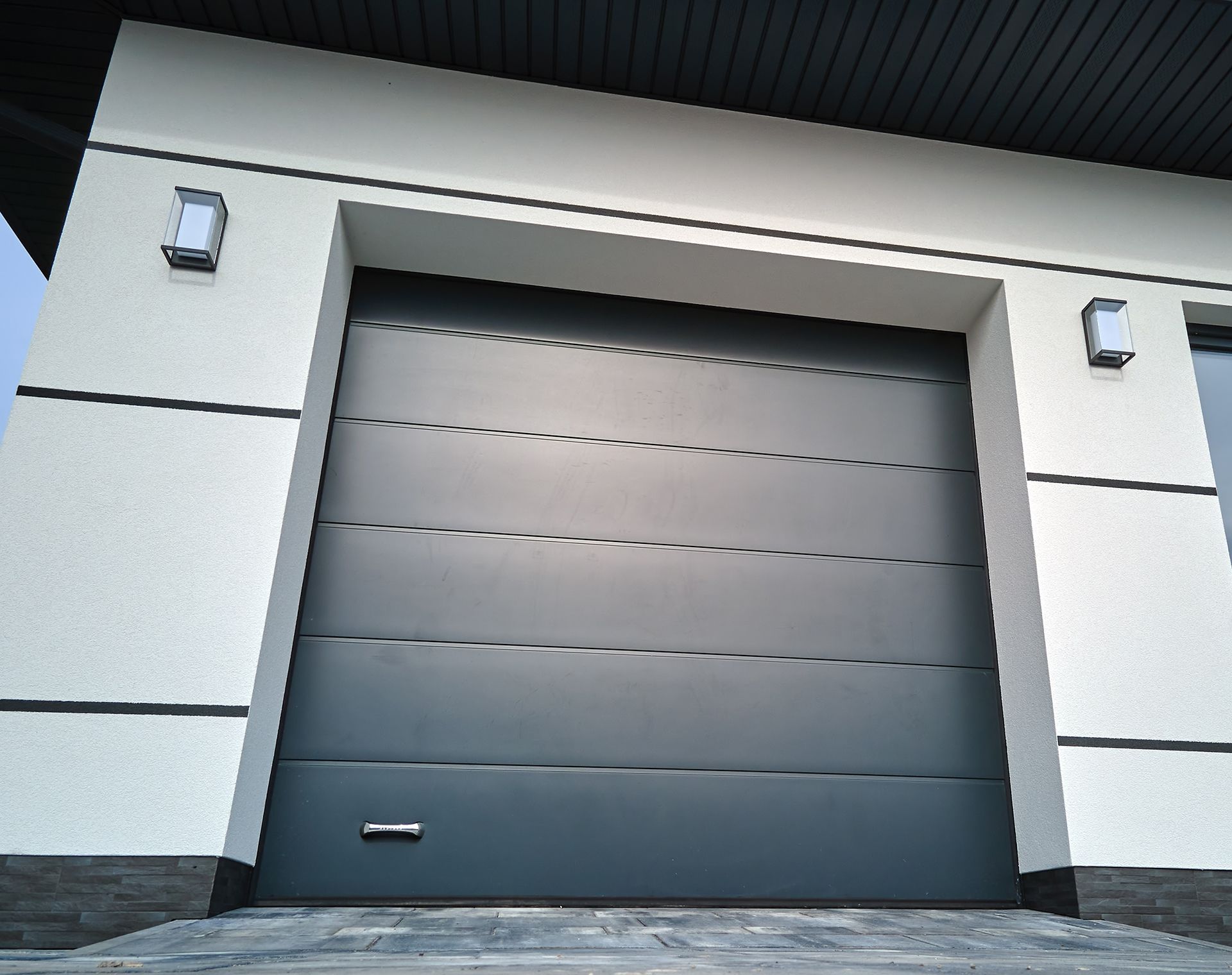 A black garage door is open on the side of a building