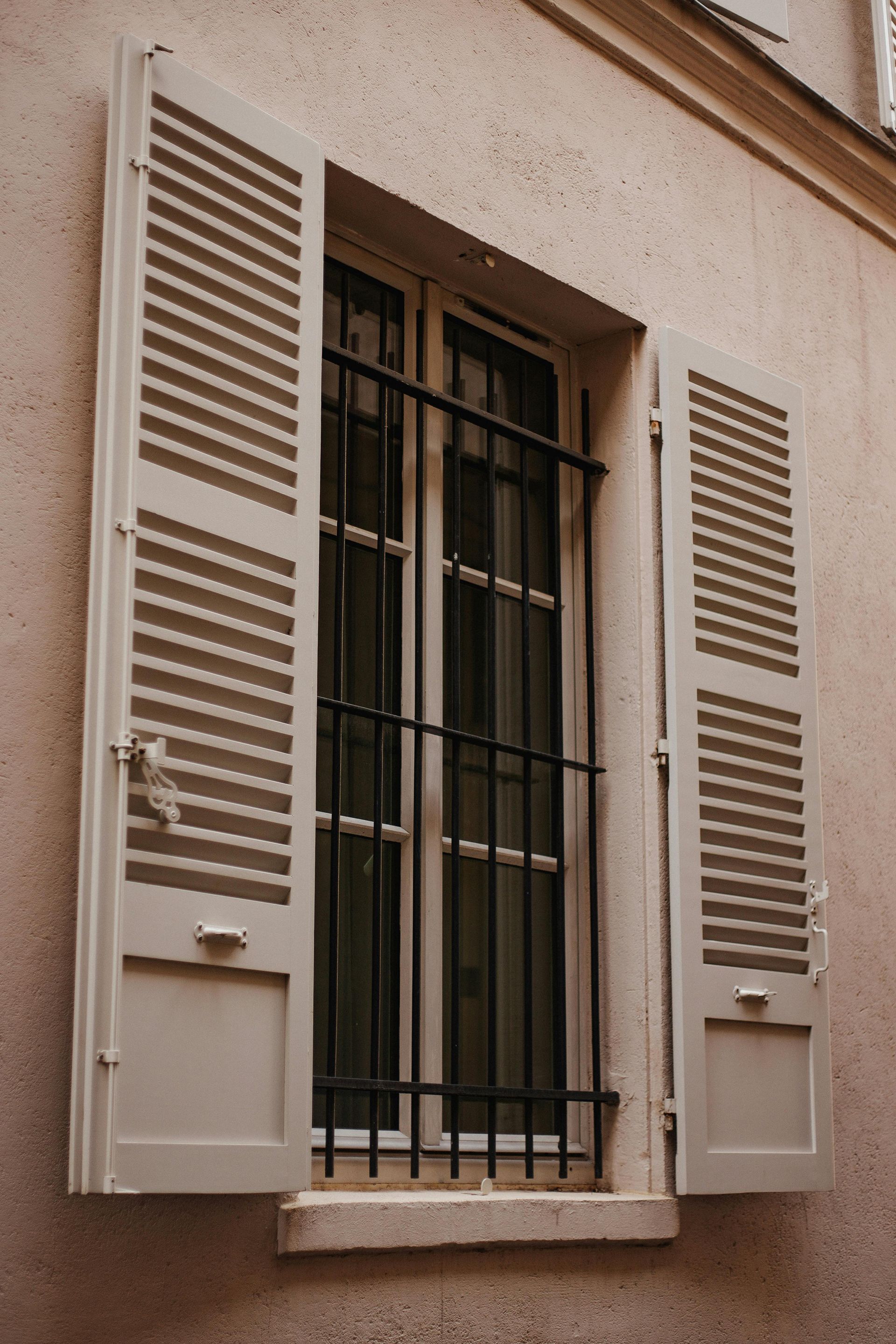 A window with shutters and bars on it on a building