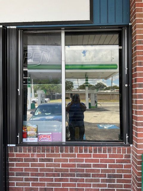 A woman is standing in front of a window at a gas station
