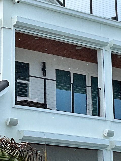 A white building with a balcony and shutters on the windows