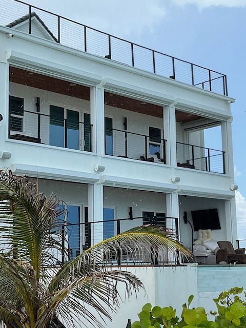 A large white house with a balcony and a palm tree in front of it