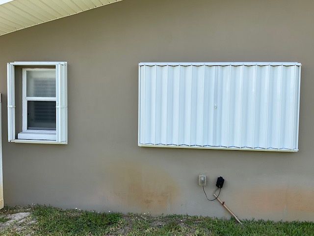 A house with two windows and a white shutter on the side of it