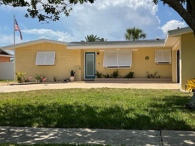 A yellow house with a blue door and shutters on the windows