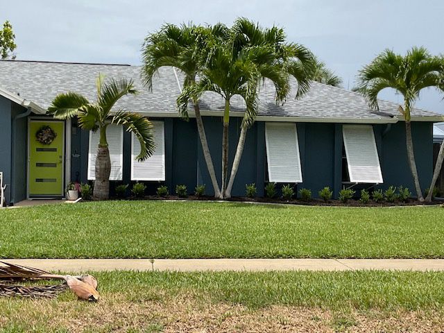 A blue house with a yellow door and palm trees in front of it
