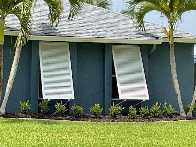 A blue house with white shutters on the windows
