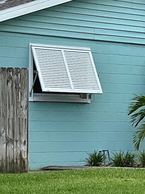A blue house with a white window with shutters on it