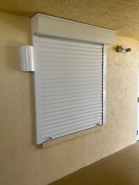 A white roller shutter is on a window on a building
