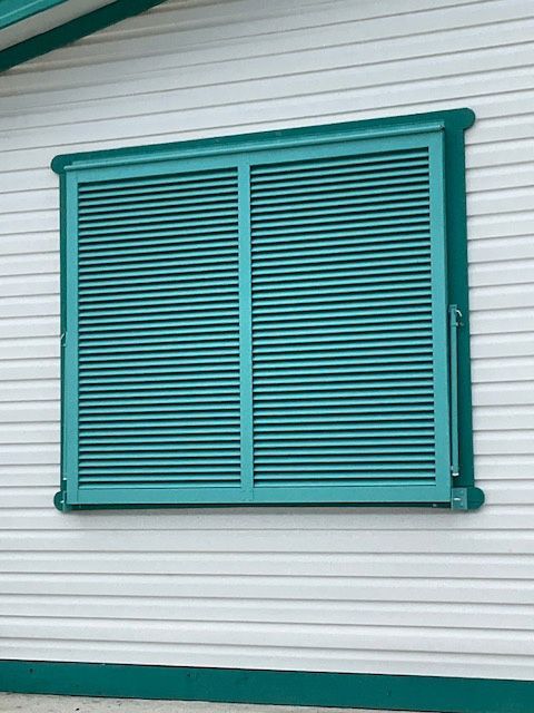 A window with green shutters on a white house