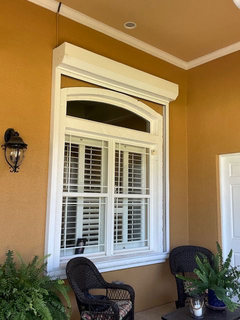 A porch with a large window and a chair