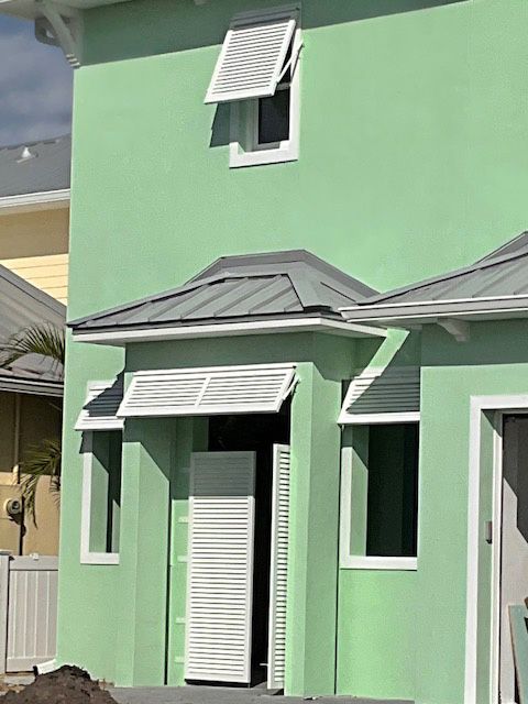 A green house with white shutters on the windows