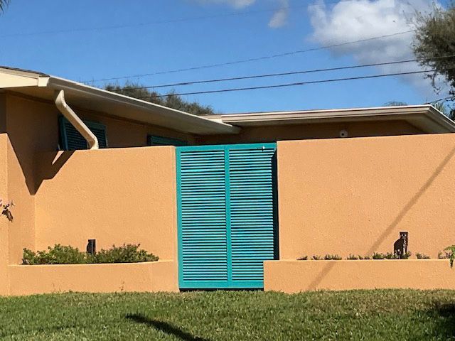 A brown house with a blue gate in front of it