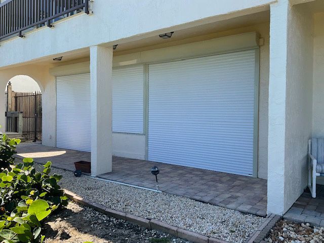A white house with a patio and shutters on the windows