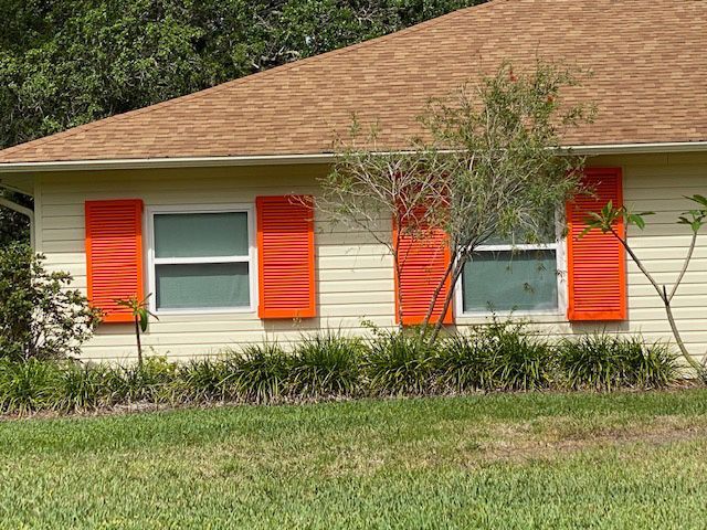 A white house with orange shutters on the windows