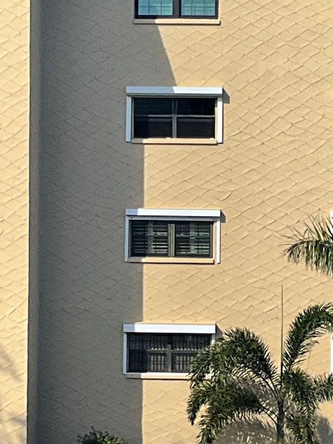 A tall building with a lot of windows and a palm tree in front of it