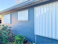 A blue house with white shutters on the windows