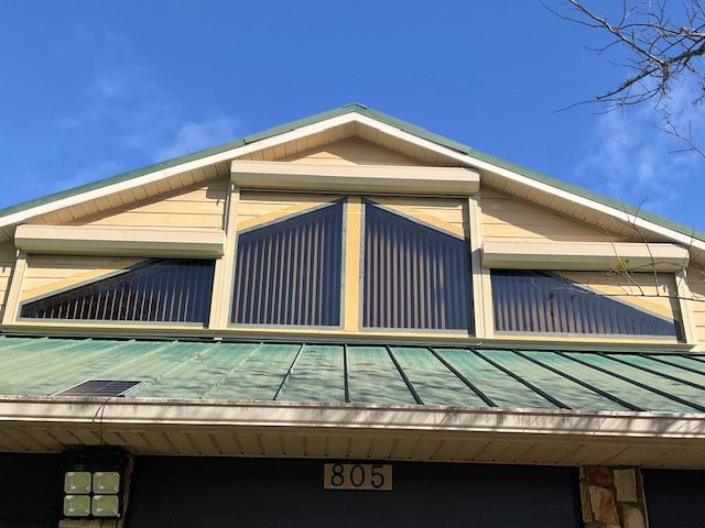 A house with a green roof and shutters on the windows