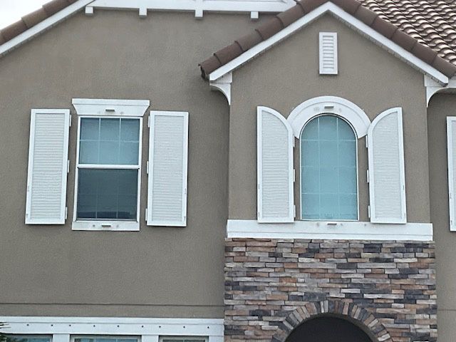 A brown house with white shutters on the windows