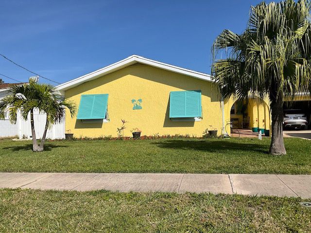 A yellow house with green shutters on the windows