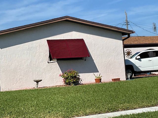 A white car is parked in front of a house with a red awning