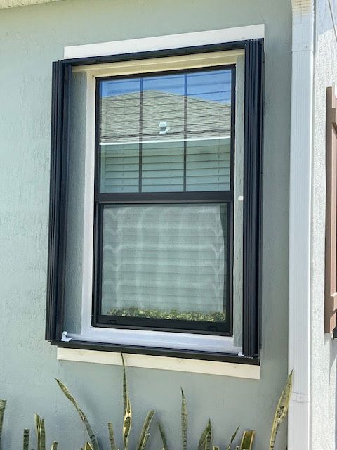 A window on the side of a house with shutters