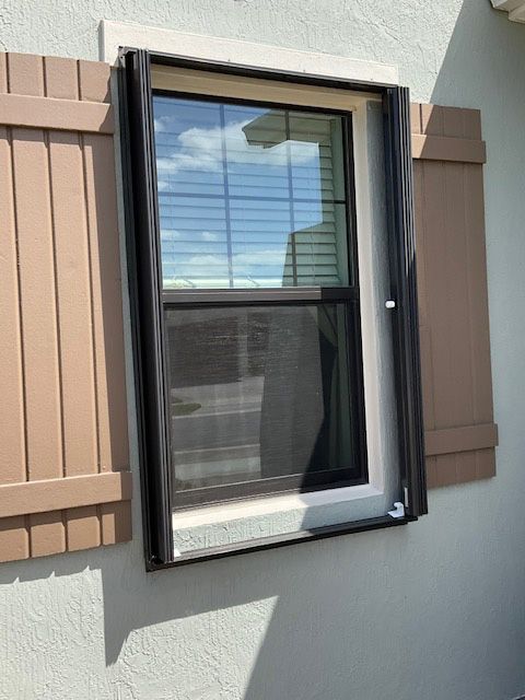 A window with brown shutters on the side of a house
