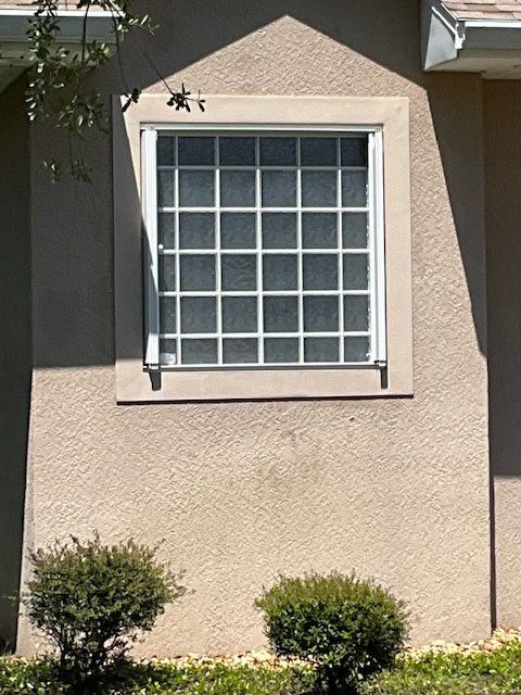 A window on the side of a house with a white frame