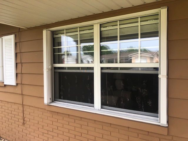 A brown brick house with a white window and white shutters