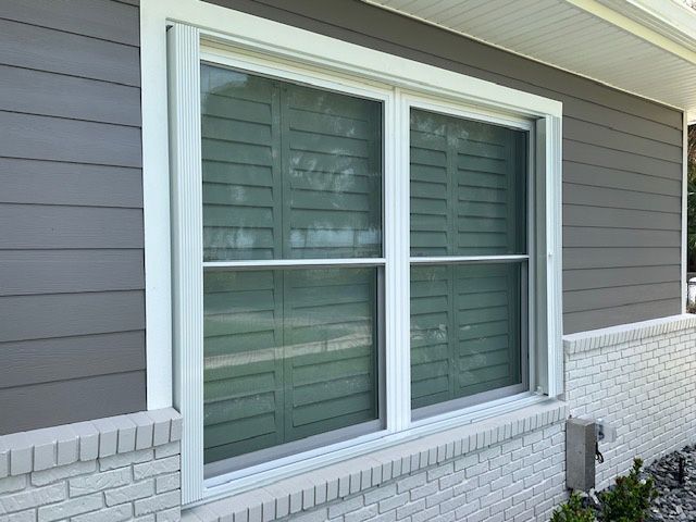 A large window on the side of a house with shutters